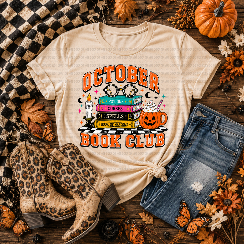 Cream T-shirt with October Book Club lettering, potion books, a candle, glasses, and a pumpkin mug