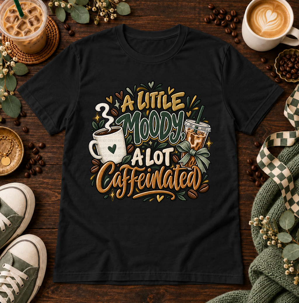 Black graphic T-shirt with coffee cups and the phrase A Little Moody, A Lot Caffeinated