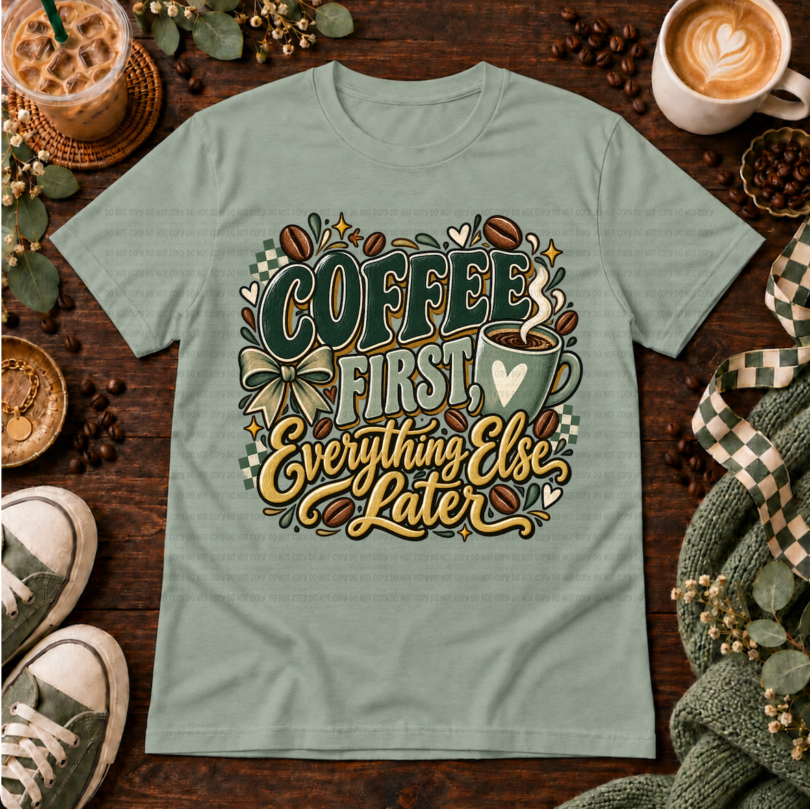Sage green graphic T-shirt with coffee beans, a coffee cup, bow, and the phrase Coffee First Everything Else Later