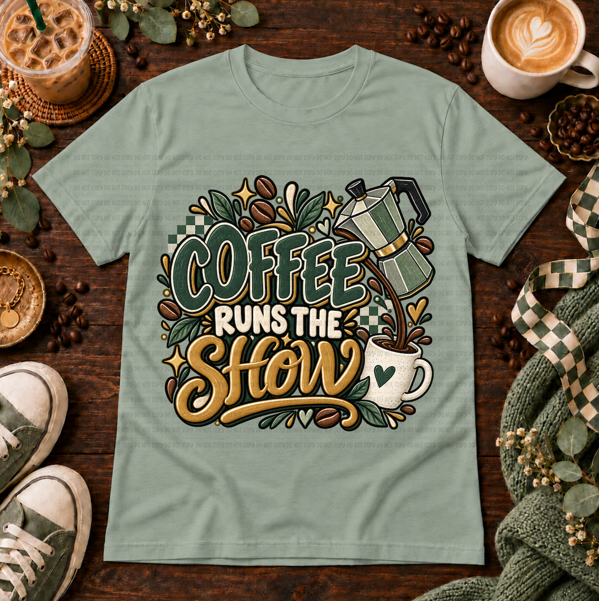 Sage green graphic T-shirt with a moka pot, coffee cup, coffee beans, and the phrase Coffee Runs the Show