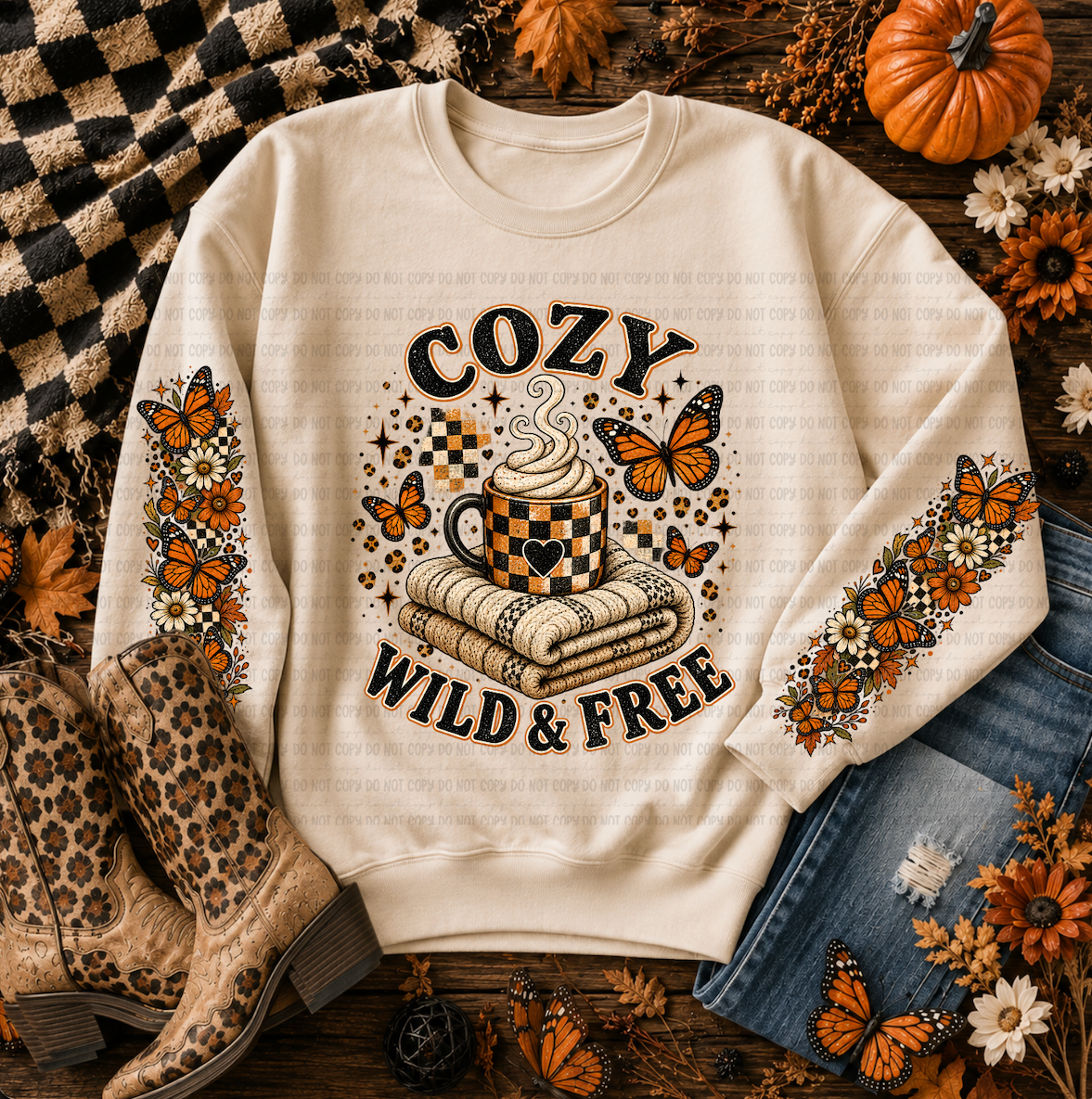 Cream sweatshirt with orange butterflies, flowers, a checkerboard coffee mug, folded blankets, and the phrase Cozy Wild and Free