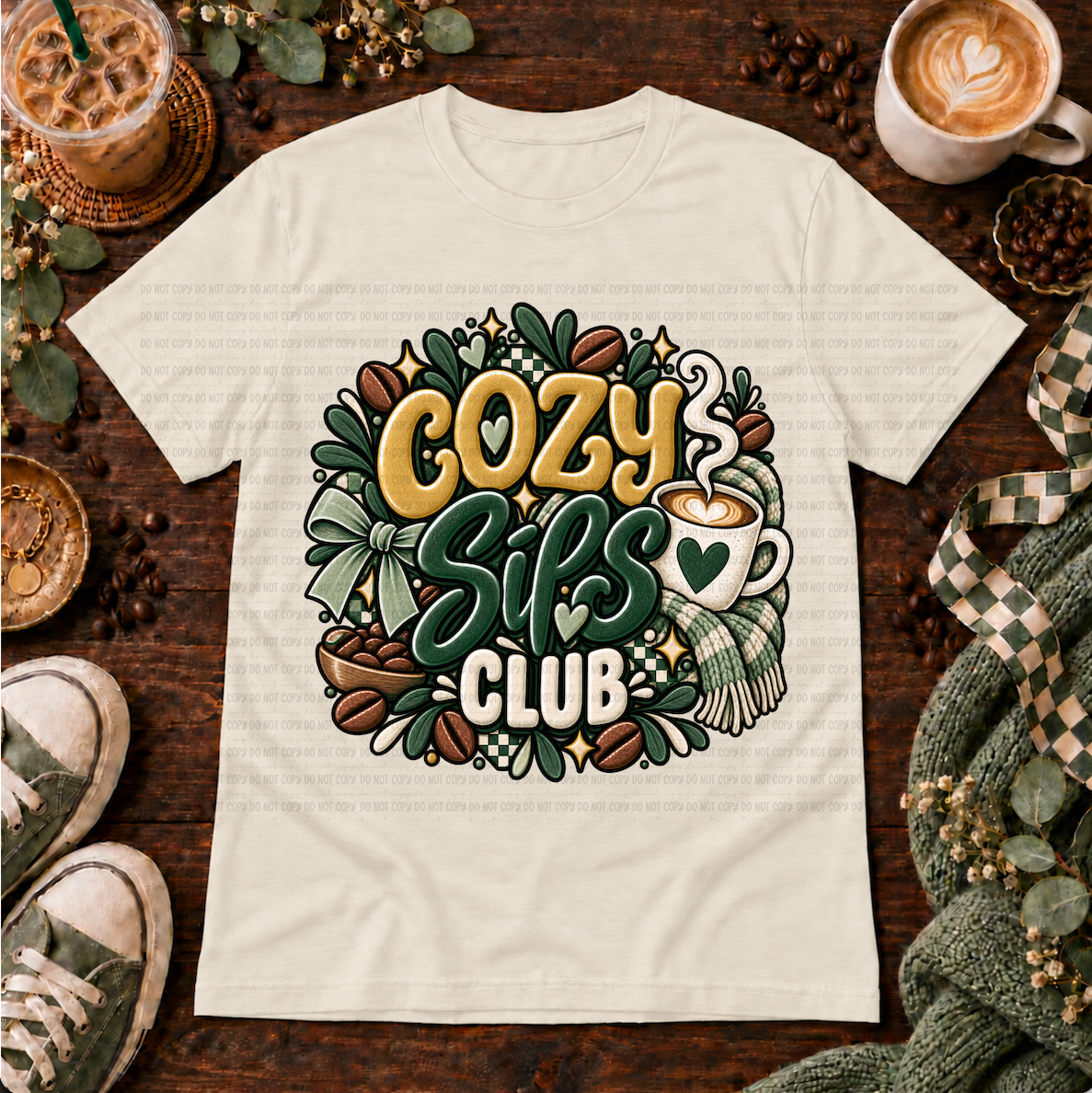 Cream graphic T-shirt with a coffee cup, scarf, coffee beans, bow, and the phrase Cozy Sips Club