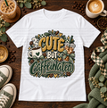 White graphic T-shirt with hot and iced coffee, bows, coffee beans, and the phrase Cute but Caffeinated