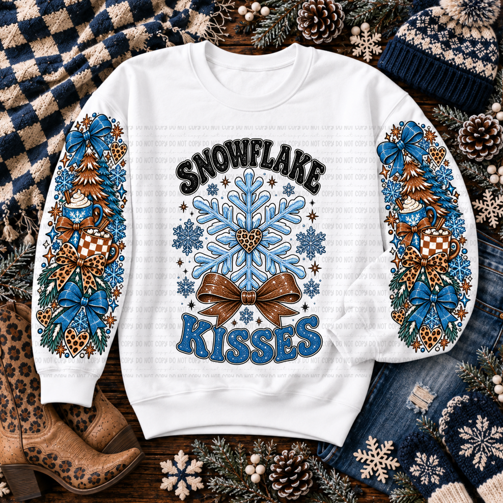 White sweatshirt with Snowflake Kisses lettering, blue snowflakes, mugs, evergreen trees, and bows