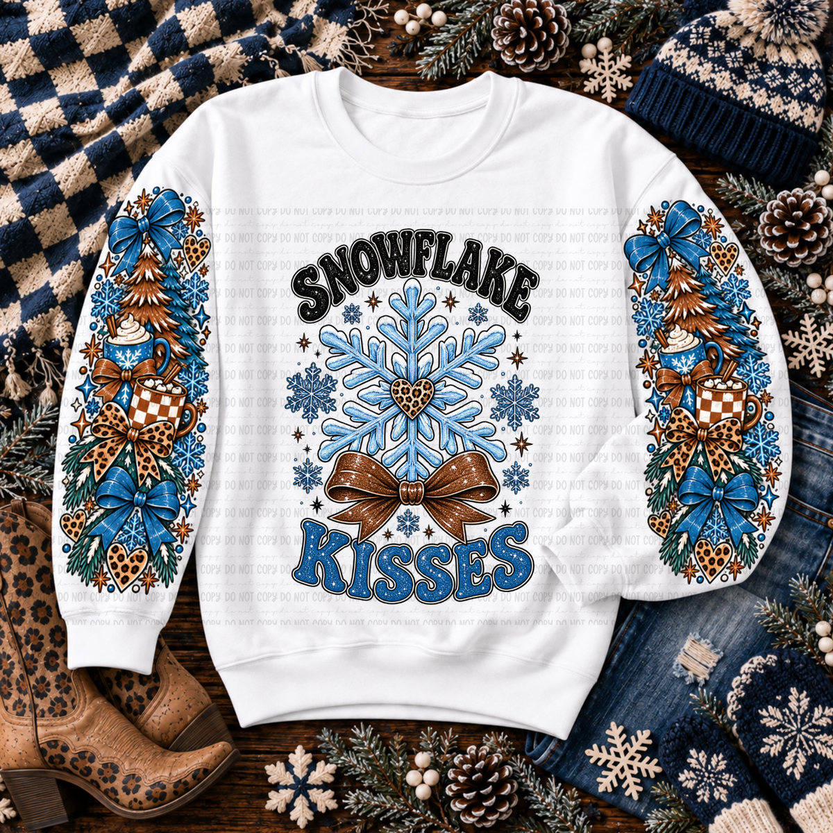 White sweatshirt with Snowflake Kisses lettering, blue snowflakes, mugs, evergreen trees, and bows