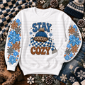 White sweatshirt with Stay Cozy lettering, blue knit hat, checkered scarf, and colorful snowflakes