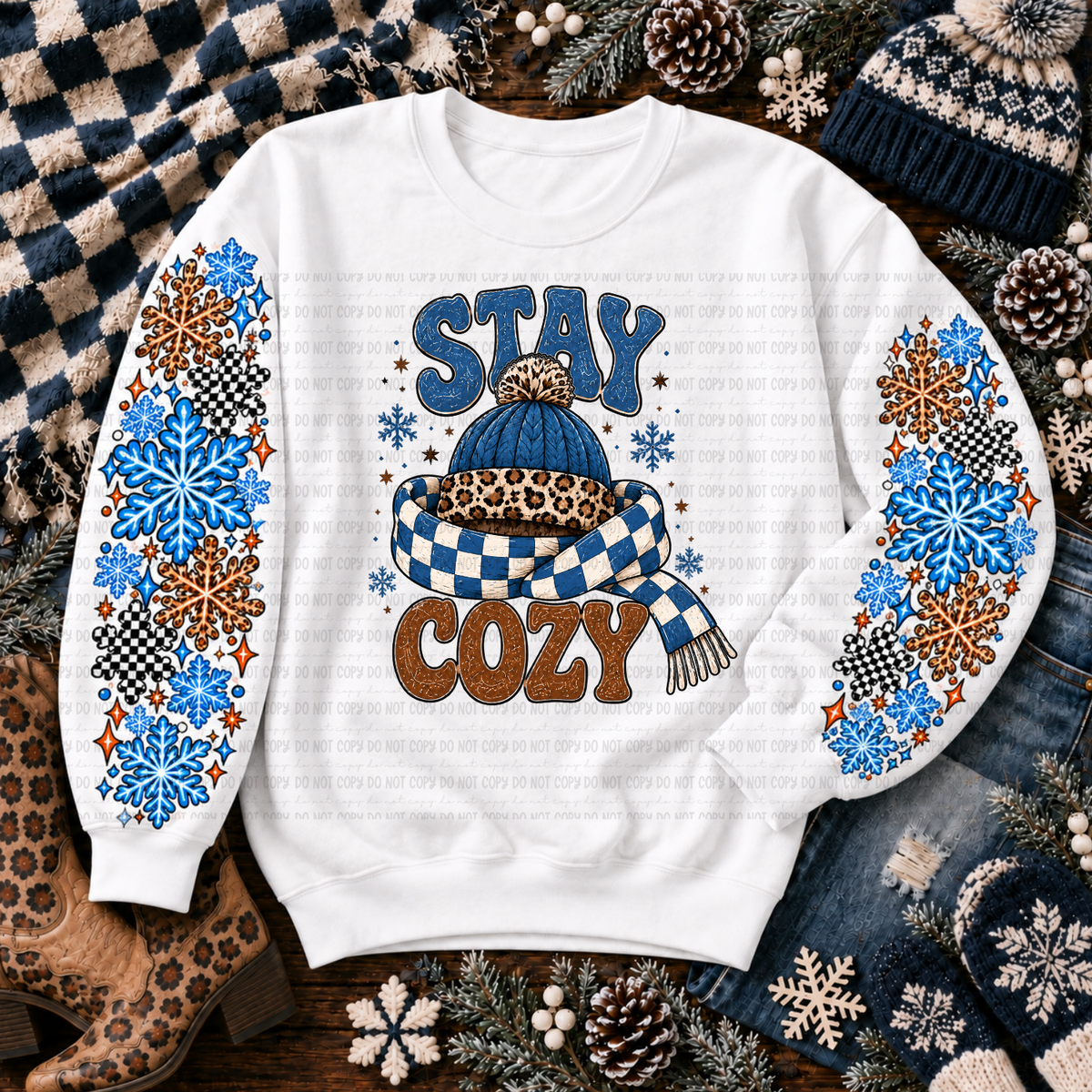 White sweatshirt with Stay Cozy lettering, blue knit hat, checkered scarf, and colorful snowflakes