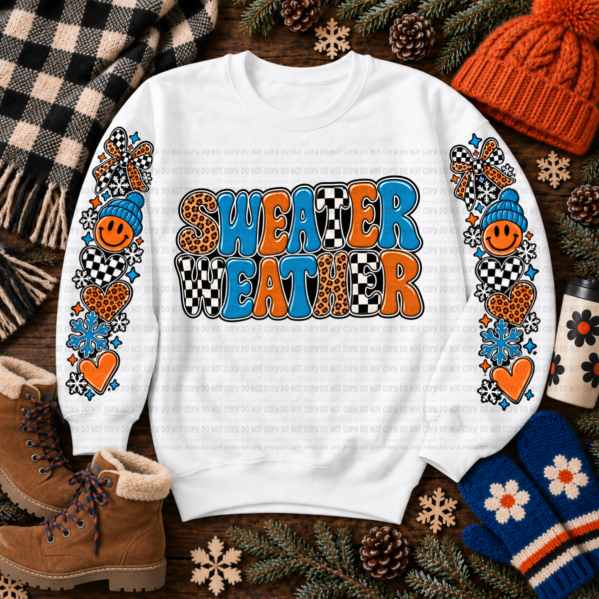 White sweatshirt with colorful Sweater Weather lettering, snowflakes, bows, hearts, and checkerboard details